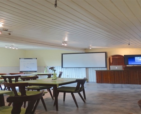 Seminarraum des Hundezentrum Pfalz mit Tischen, Stühlen, Leinwand und Bildschirm